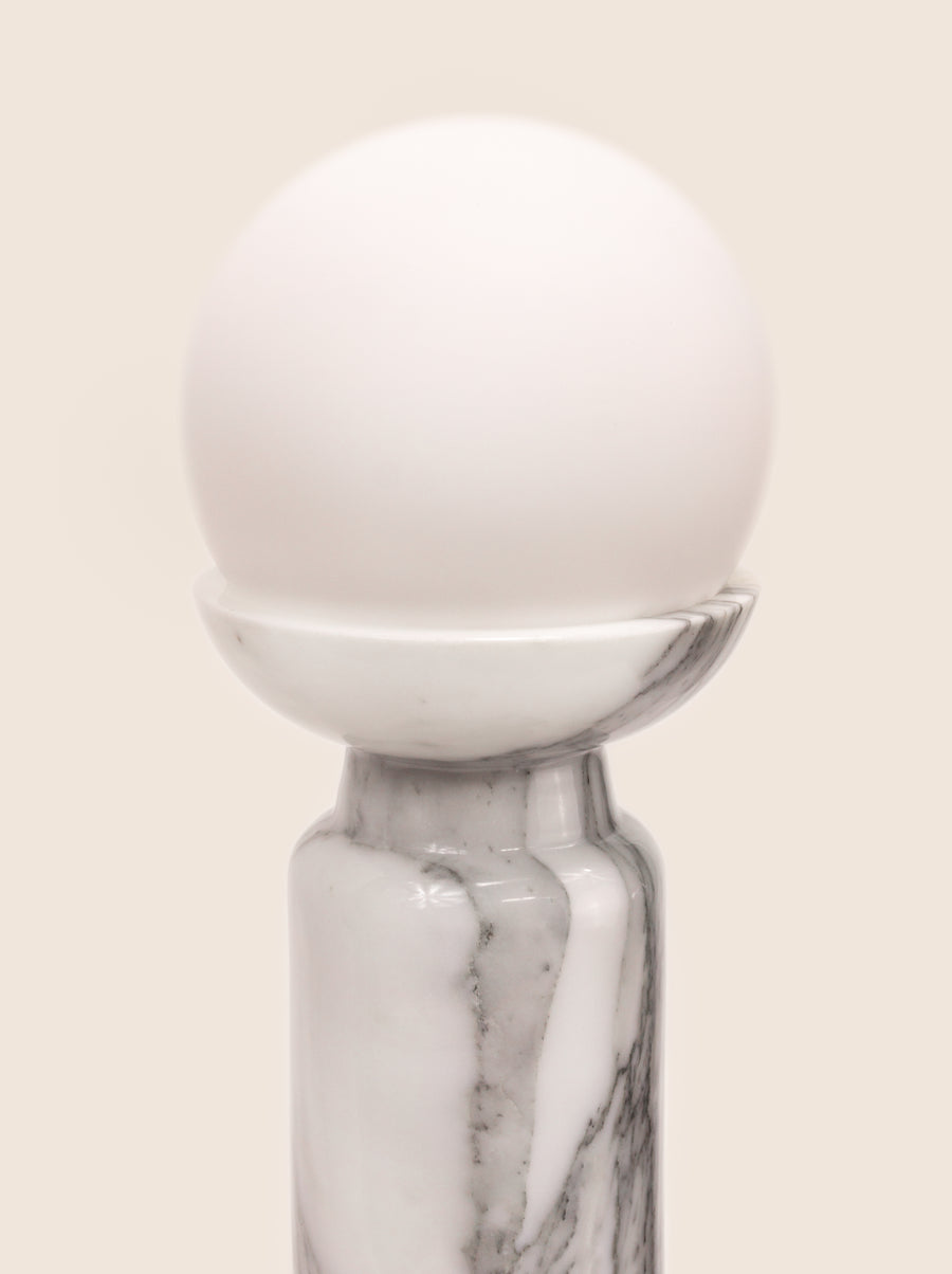 Folsom table lamp with sculptural marble base and glass or globe bulb.